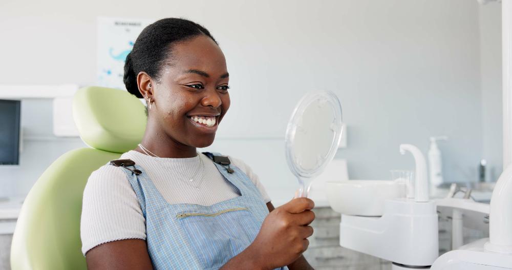 Black woman smiling into mirror in dental chair, clintonville oh