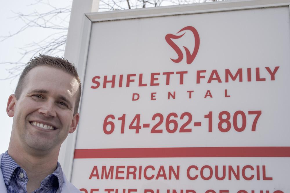 Dr. Justin Shiflett in front of a sign for his office, clintonville oh