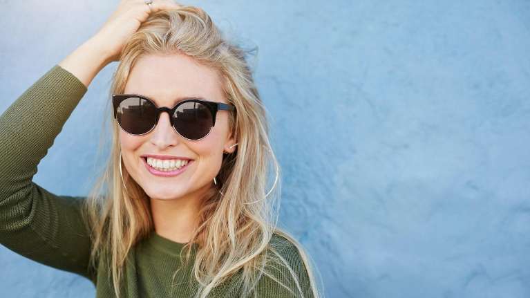 A lady wearing shades smiling and flashing her white teeth in Columbus.