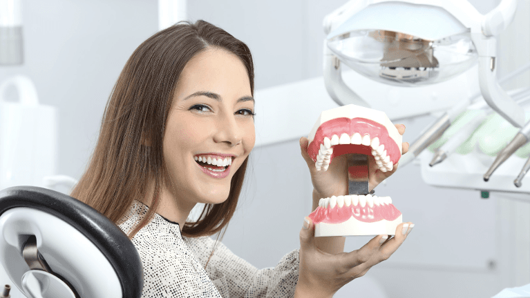 Female patient in Columbus OH holding teeth model